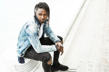 Guy young African American sitting on the street. Lifestyle of urban young people