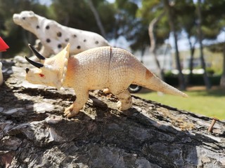 dinosaur toys on tree trunk