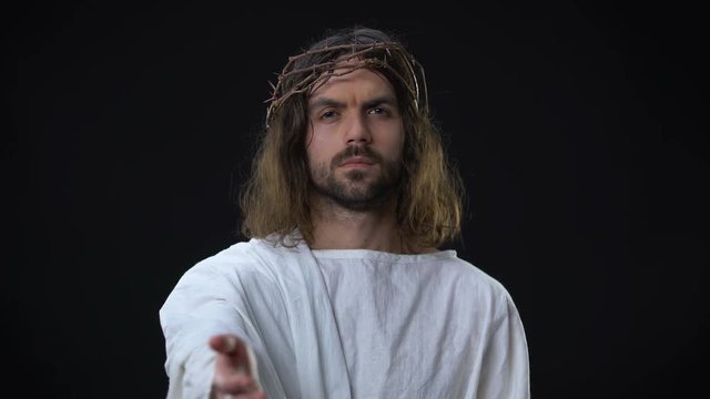 Jesus Christ with open palm on dark background, helping hand support, bible