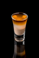 Alcoholic cocktails B-52 in shot glasses (shooters).  Cool drink from strong vodka, whiskey, coffee liqueur, baileys. Isolated on black background. Cocktail card for a bar or restaurant.