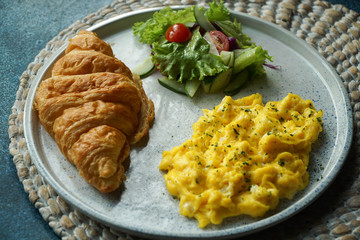 Breakfast with croissant, scrambled egg, and vegetables salad