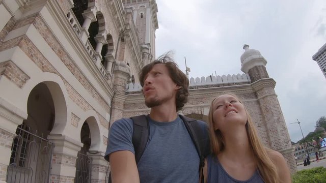 Young man and woman walking around the Sultan Abdul Samad Building in Kuala Lumpur vity, Malaysia
