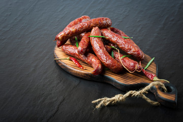 Smoked sausage with rosemary and pepper on a black background. 