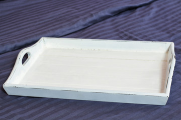 Hotel food offerings, quick service concept. Empty white tray with copy space at bedroom bed. Top view, place for meal. Freshly prepared food offering options. Takeaway delivery. Selective focus