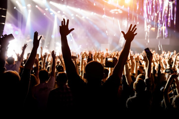 A man with his hands up at a concert of his favorite group.