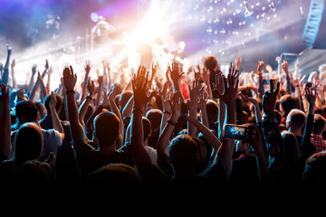 A man with his hands up at a concert of his favorite group.