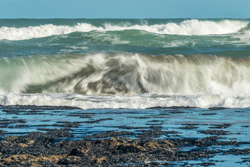 Sea waves hitting on the stones near the coast. White foam comes out of the waves white foam of a sea wave