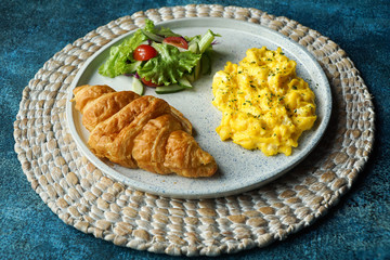 Breakfast with croissant, scrambled egg, and vegetables salad