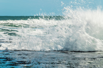 Sea waves hitting on the stones near the coast. White foam comes out of the waves white foam of a sea wave