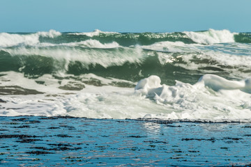 Sea waves hitting on the stones near the coast. White foam comes out of the waves white foam of a sea wave