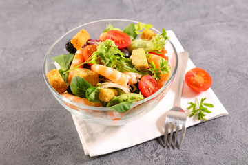 bowl of shrimp salad with tomato, olive and crouton