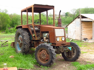 Obraz premium an old tractor, a rusty body, a wooden room, a green courtyard