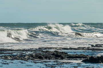 Sea waves hitting on the stones near the coast. White foam comes out of the waves white foam of a sea wave