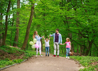 Fototapeta premium Family father and mother with two kids walking in summer green city park on picnic, happy holidays parents and children on nature