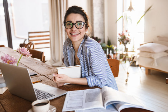 Image of cute young woman 20s typing on laptop while working or studying at home