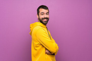 Handsome man with yellow sweatshirt with arms crossed and looking forward