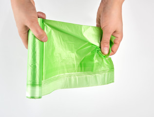female hand unwind green roll with plastic bags for garbage