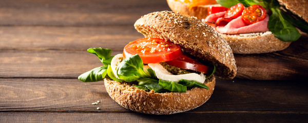 Italian Caprese sandwiches with fresh tomatoes, mozzarella cheese and lamb's lettuce, multigrain bun. Healthy food concept with copy space