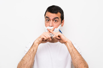 Man shaving his beard over isolated white background showing a sign of silence gesture