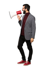 Handsome man with glasses shouting through a megaphone over isolated white background