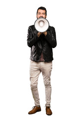 Handsome man with beard shouting through a megaphone over isolated white background