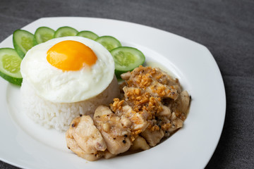 Rice,Fried egg,Fried chicken with garlic and black pepper in white dish on the concrete table.