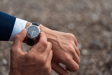 A man in a business suit checking a wrist watch on his hand on background  sea