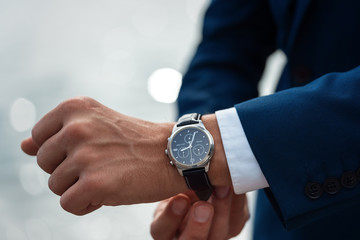 A man in a business suit checking a wrist watch on his hand on background  sea