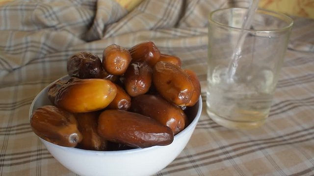 date palm in white cup and pouring water into a glass concept for pre-fast meal in ramadan fasting