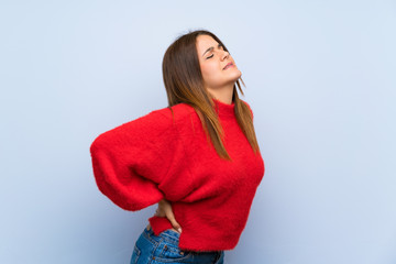 Young woman over isolated blue wall suffering from backache for having made an effort