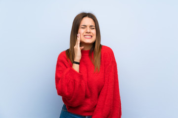 Fototapeta premium Young woman over isolated blue wall with toothache
