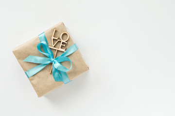 Gift box wrapped in brown paper with blue ribbon on white background. Top view. Copyspace