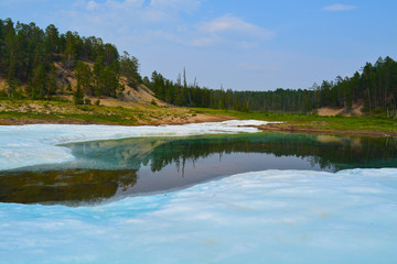 Lake with ice and green forest