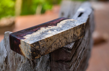 Fototapeta premium Afzelia burl wood bar casting with epoxy resin Stabilizing for blanks on blurred background