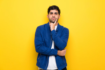 Fototapeta premium Man with blue jacket over yellow wall Looking front