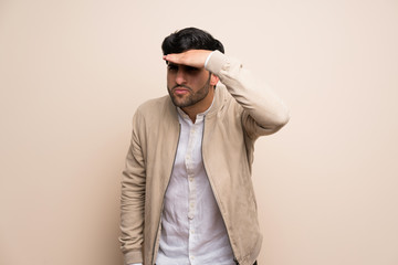 Young man over isolated wall looking far away with hand to look something