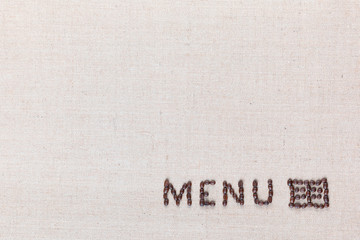Menu word with icon made from roasted coffee beans on linen creamy linen canvas, shot from above, aligned bottom right.