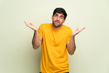 Young man over pink wall making unimportant gesture while lifting the shoulders