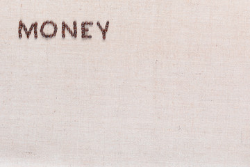 Money written with coffee beans on linen texture, arranged top left.