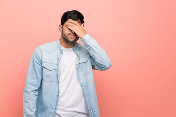Young man over pink wall covering eyes by hands. Do not want to see something