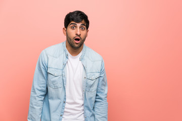 Young man over pink wall with surprise facial expression