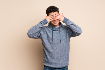 Young man over isolated wall covering eyes by hands