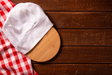 Chef hat with cutting board on wooden table