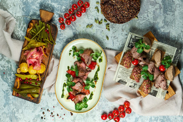 Cold meat snacks with pickled vegetables. Beautiful serving of dishes. Light gray background. Restaurant menu