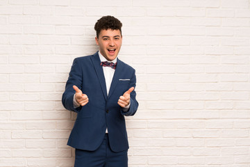 Man in suit and bow tie pointing to the front and smiling