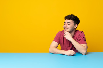 Young man with colorful wall and table looking to the side