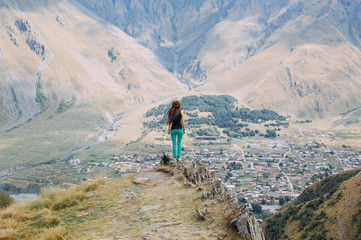 Fototapeta na wymiar Travel woman, wanderlust concept. Woman traveler with dreadlocks on a mountain in Kazbegi, Georgia.