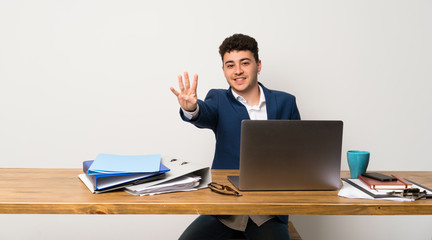 Business man in a office happy and counting four with fingers