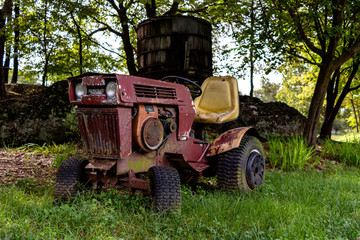 Rusty and vintage riding lawn mower in a vineyard