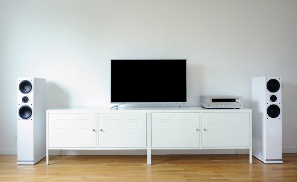 Modern audio stereo system with white speakers on bureau in modern interior